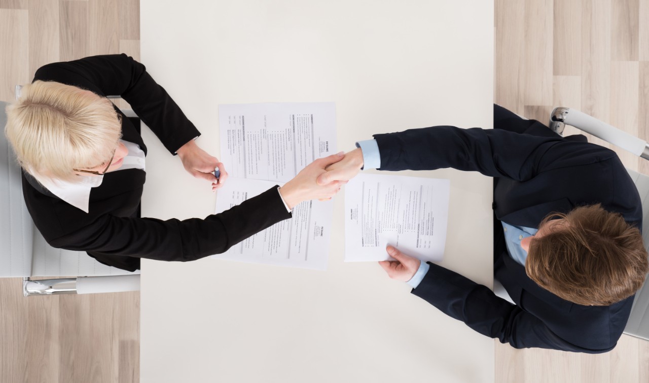 High Angle View Of Two Businesspeople Shaking Hand In Office