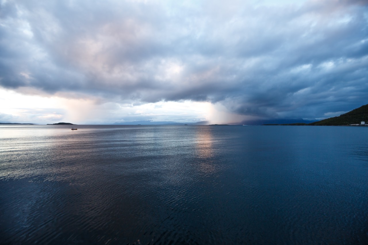 Landscape with sea and clouds in the midnight of polar day in Harstad, Norway.