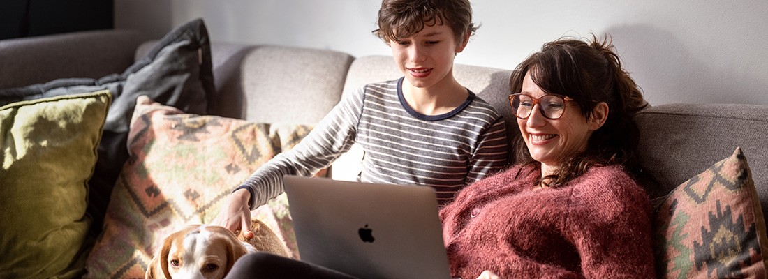 mor og sønn ser på pc i sofa