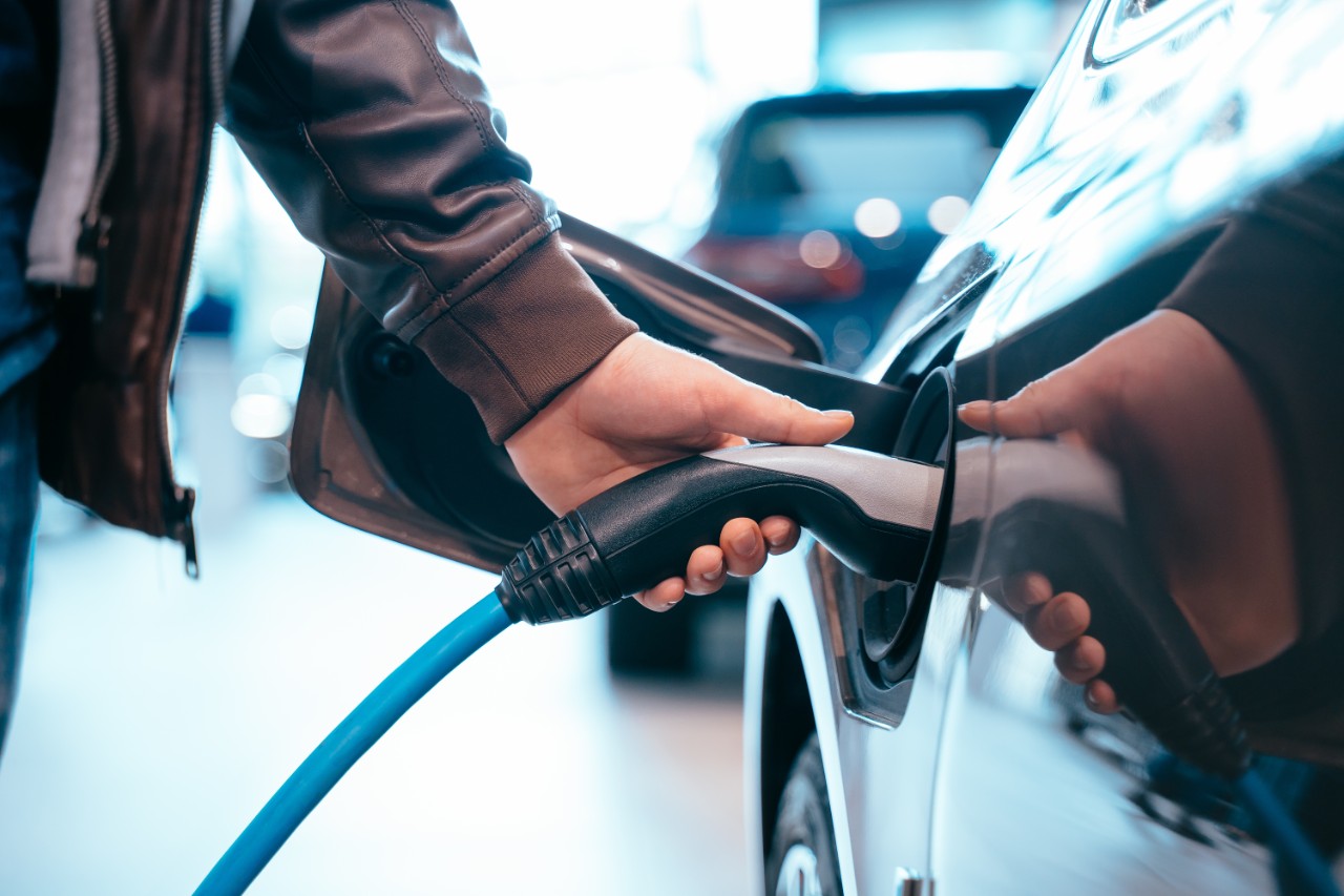Closes up Human hand is holding Electric Car Charging connect to Electric car