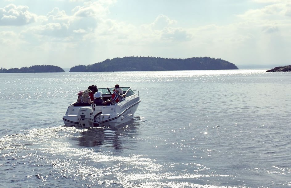 båt på vei ut i oslo fjorden en sommerdag med sjåfør som har tatt båtførerprøven